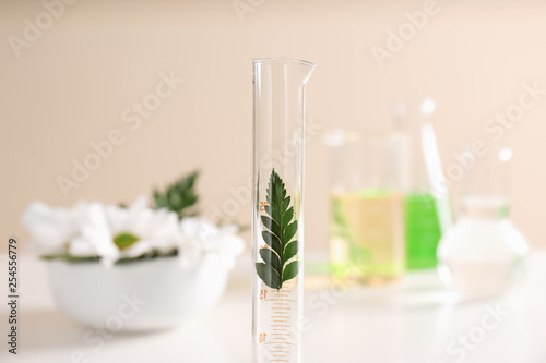 Graduated cylinder with leaf on table. Dermatology equipment