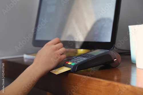 Woman using credit card machine for non cash payment in cafe, closeup photo