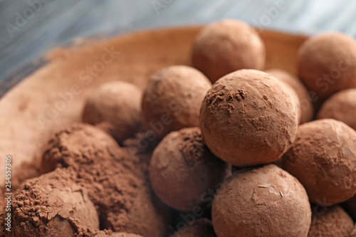 Plate with chocolate truffles on table, closeup