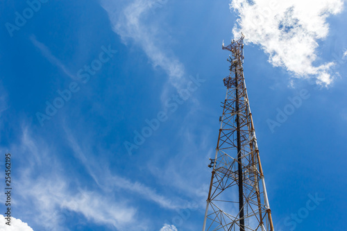 Mobile phone communication repeater antenna tower, with blue sky and white clouds.
