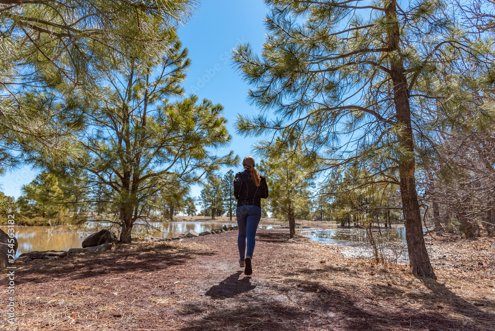 Wide shot of female runner with red hair running away from the camera on a beautiful winter day, Wide shot of female runner with red hair running away from the camera on a beautiful winter day,