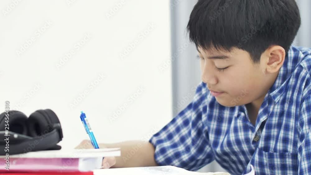 Asian cute boy doing your homework with smile face at home ,4K Dolly shot. Asian cute boy doing your homework with smile face at home ,4K Dolly shot.