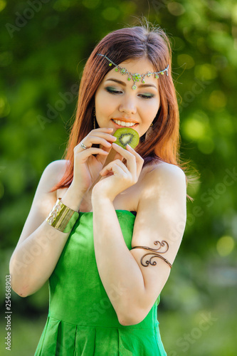 Beautiful young asian woman biting slice of kiwi