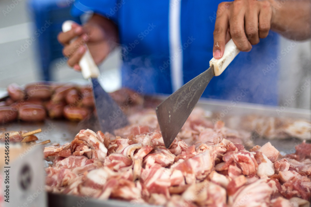 Cuts of pork and beef being cooked at a street food cart in Medellin, Colombia