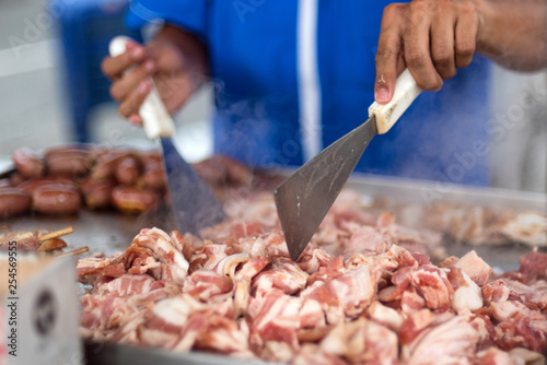 Cuts of pork and beef being cooked at a street food cart in Medellin, Colombia