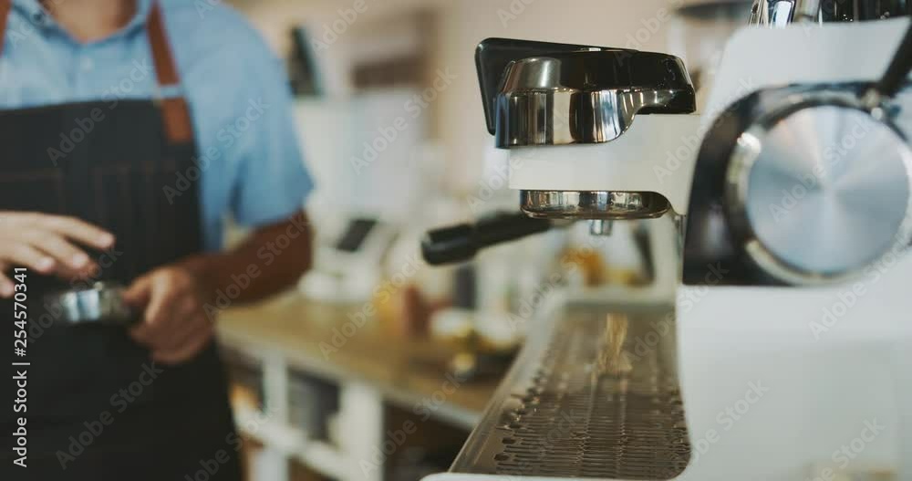 Attractive young barista preparing delicious coffee, barista using espresso machine, coffee shop lifestyle