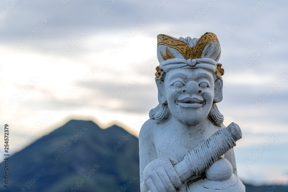 Traditional Balinese sculpture against the background of the volcano Batur on sunrise, morning time. Island Bali, Indonesia. Closeup Traditional Balinese sculpture against the background of the volcano Batur on sunrise, morning time. Island Bali, Indonesia. Closeup