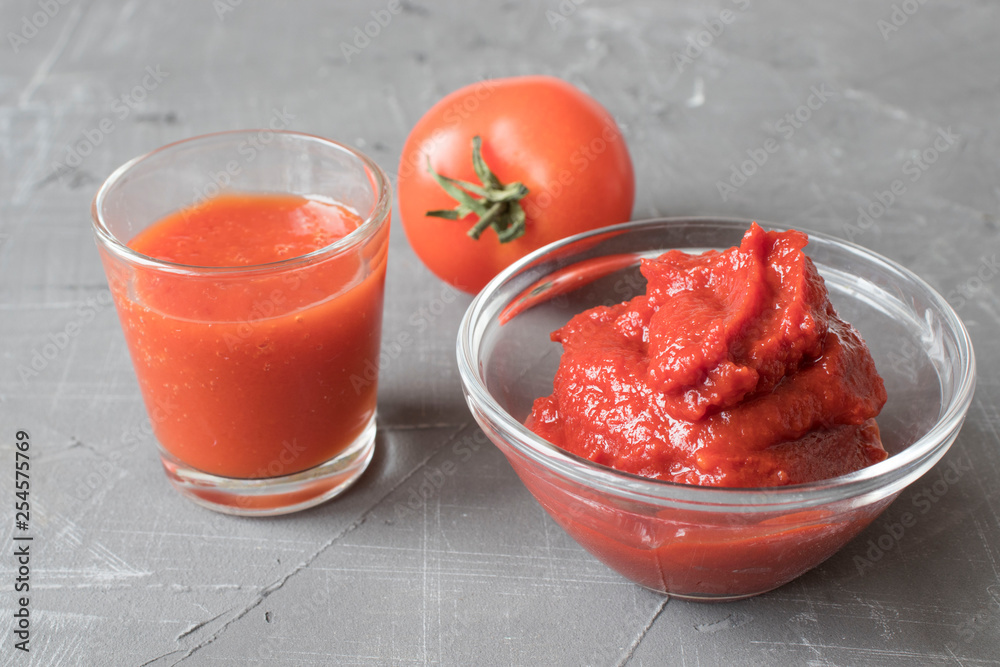 tomato juice in cups and tomato paste on a concrete background, selective focus tomato juice in cups and tomato paste on a concrete background, selective focus