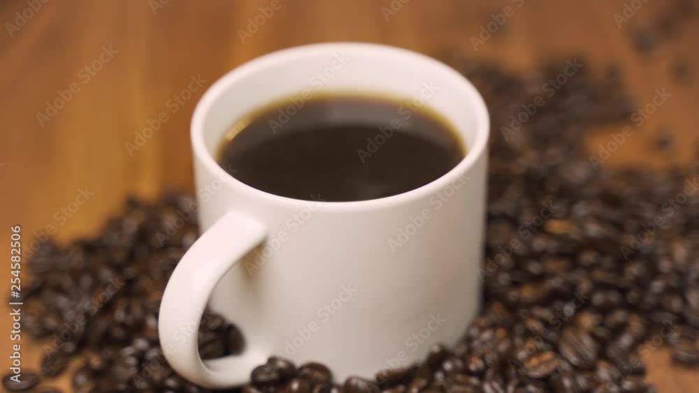Pan shot of coffee cup surrounded by coffee beans. Pan shot of coffee cup surrounded by coffee beans.