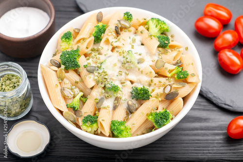 Pasta with broccoli, green onion and pumpkin seeds, sprinkled with white sauce