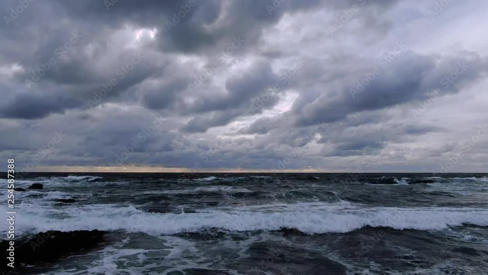 Cloudy sunset deep blue waves crashing on rocky seashore birds and beach Cloudy sunset deep blue waves crashing on rocky seashore birds and beach