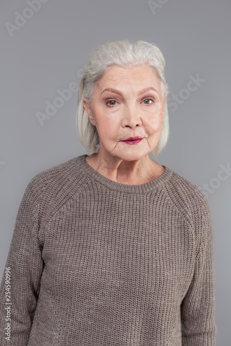 Obraz na plátně Old woman with bob haircut having, dark lipstick while wearing grey sweater