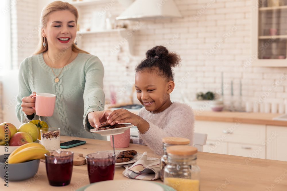Loving caring mother giving her cute girl plate with cookies Loving caring mother giving her cute girl plate with cookies