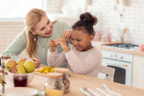 Mother and daughter having much fun cutting vegetables for salad