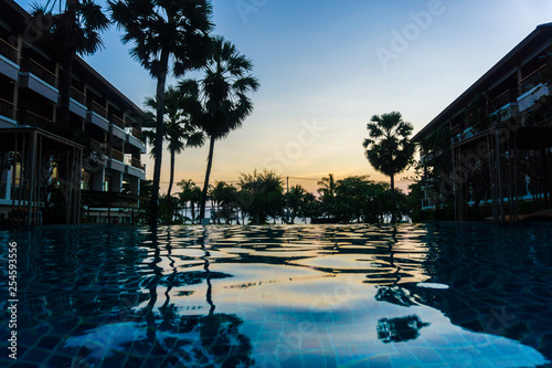 Silhouette palm tree sunset in modern resort with swimming pool