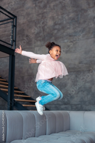 Fototapeta Naklejka Na Ścianę i Meble -  Daughter going crazy staying home alone and jumping