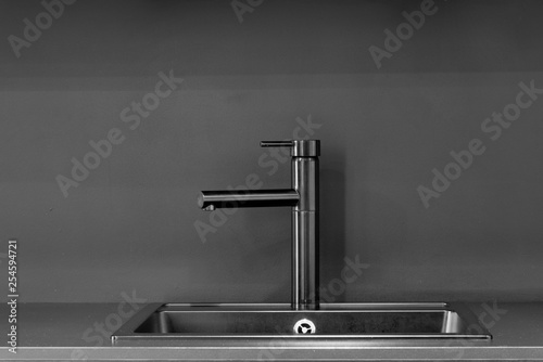 Black faucet with black sink, black table top and black wall