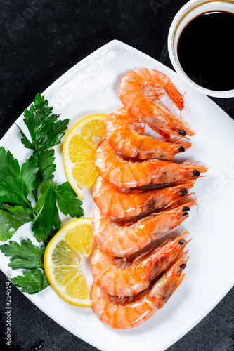 Grilled prawns with soy sauce, lemon and herbs. Royal delicious and beautiful shrimp on black background. Flatley. Food background