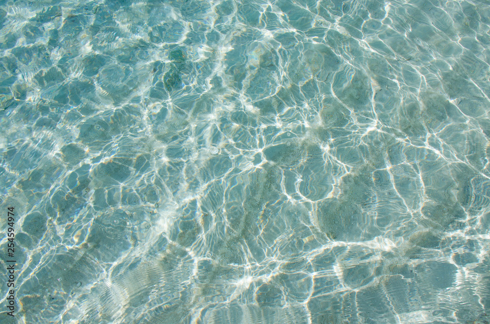 Natural background of turquoise water of the ocean with patches of light of the sun