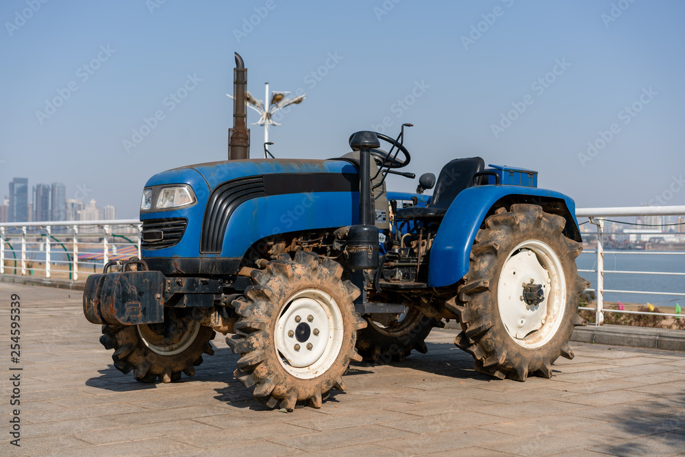 Blue tractor on the background of an empty field and a clear blue sky Blue tractor on the background of an empty field and a clear blue sky