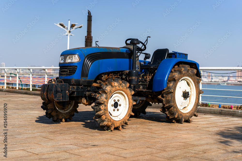 Blue tractor on the background of an empty field and a clear blue sky Blue tractor on the background of an empty field and a clear blue sky