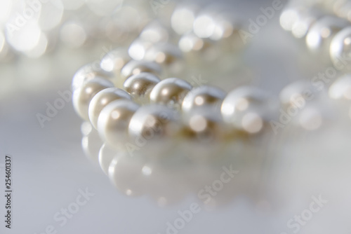 A necklace of pearls lying on white glass 