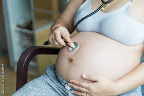 Pregnant women use stethoscope examining listen baby tummy