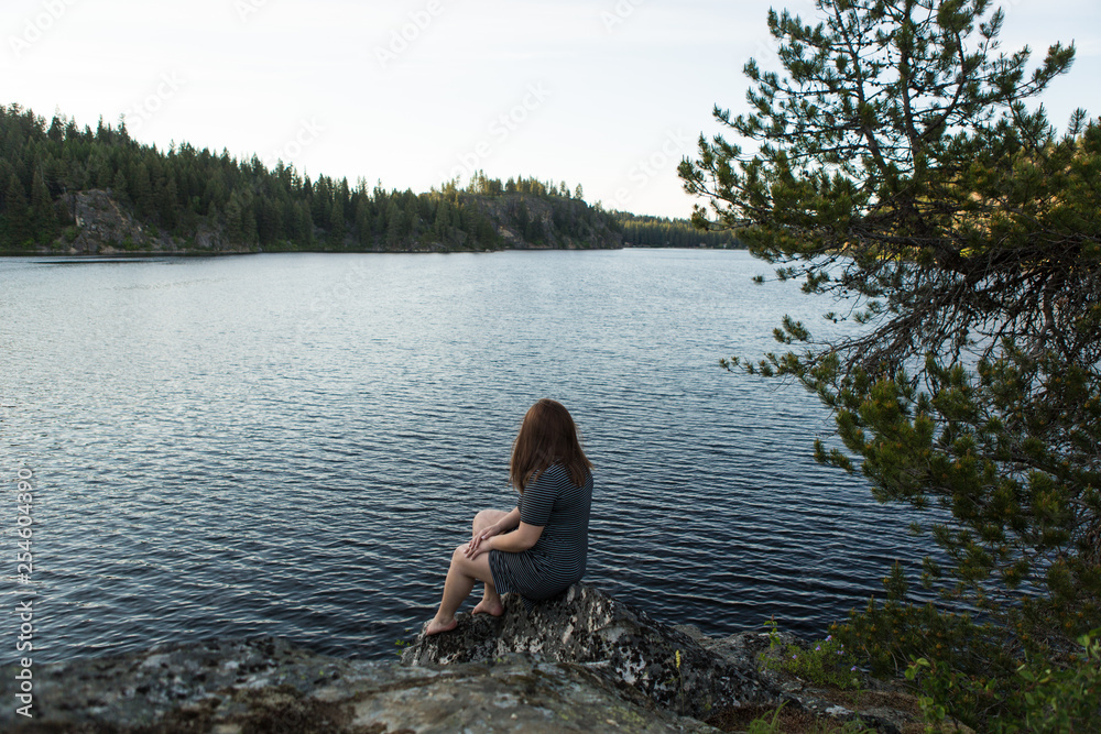 Girl sitting on rock overlooking lake Girl sitting on rock overlooking lake