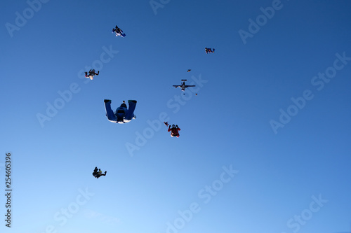 Skydivers are in the blue sky.