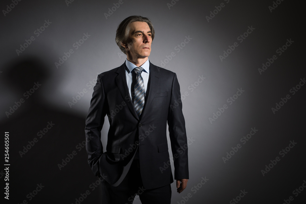 Man 50 years old in an elegant suit on a dark background. Men's fashion. Man 50 years old in an elegant suit on a dark background. Men's fashion.