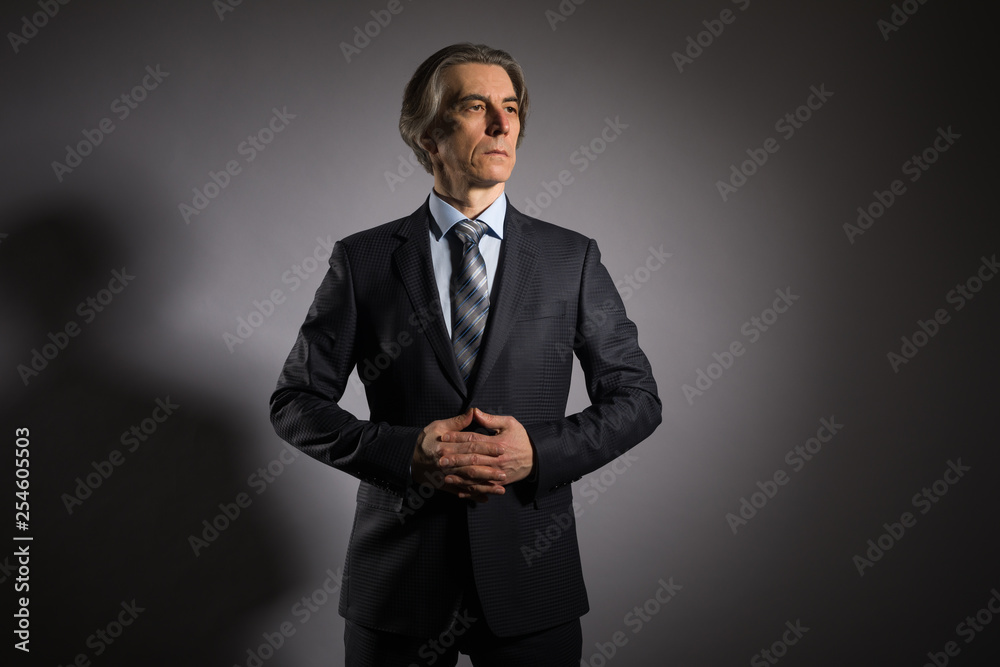 Man 50 years old in an elegant suit on a dark background. Men's fashion. Man 50 years old in an elegant suit on a dark background. Men's fashion.