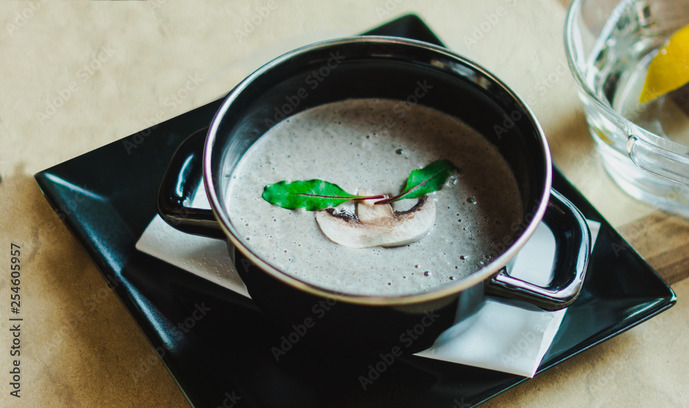 Mushroom cream soup with herbs and spices in a black bowl Mushroom cream soup with herbs and spices in a black bowl