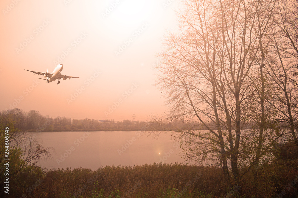 Airliner over the lake in cloudy weather. Sunset.