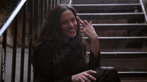 Portrait shot of a young woman doing a silly middle finger hand gesture with her tongue out