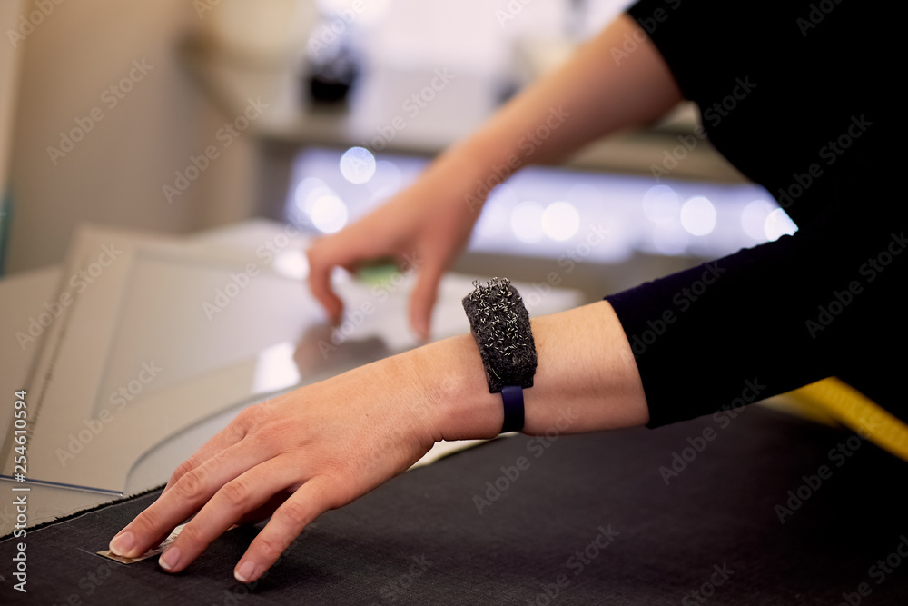Obraz premium The seamstress lays out the fabric for cutting using inches. Hands in shot.