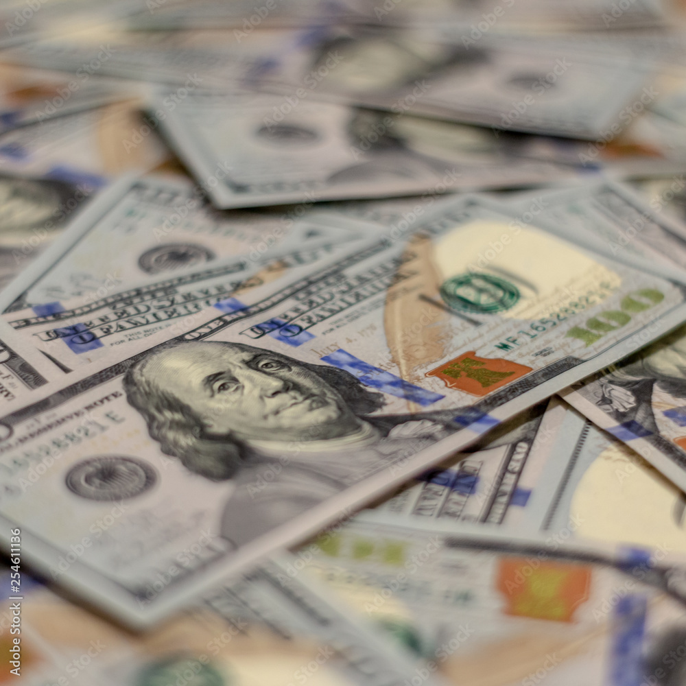 Macro shot of Benjamin Franklin's portrait on a new 100 dollar US money note, with defocused background of many more identical money notes in a mess. Macro shot of Benjamin Franklin's portrait on a new 100 dollar US money note, with defocused background of many more identical money notes in a mess.