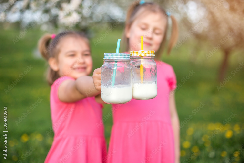 Bottles with milk in children's hands. Childhood, happiness, summer Bottles with milk in children's hands. Childhood, happiness, summer