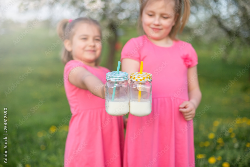Fototapeta premium Bottles with milk in children's hands. Childhood, happiness, summer