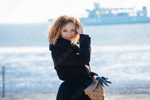 Curly girl on the background of the sea and the ship. Good mood, weekend, smile.