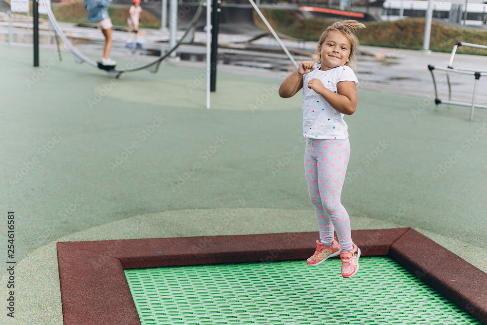 Cheerful adorable girl jumping outdoors in kindergarten