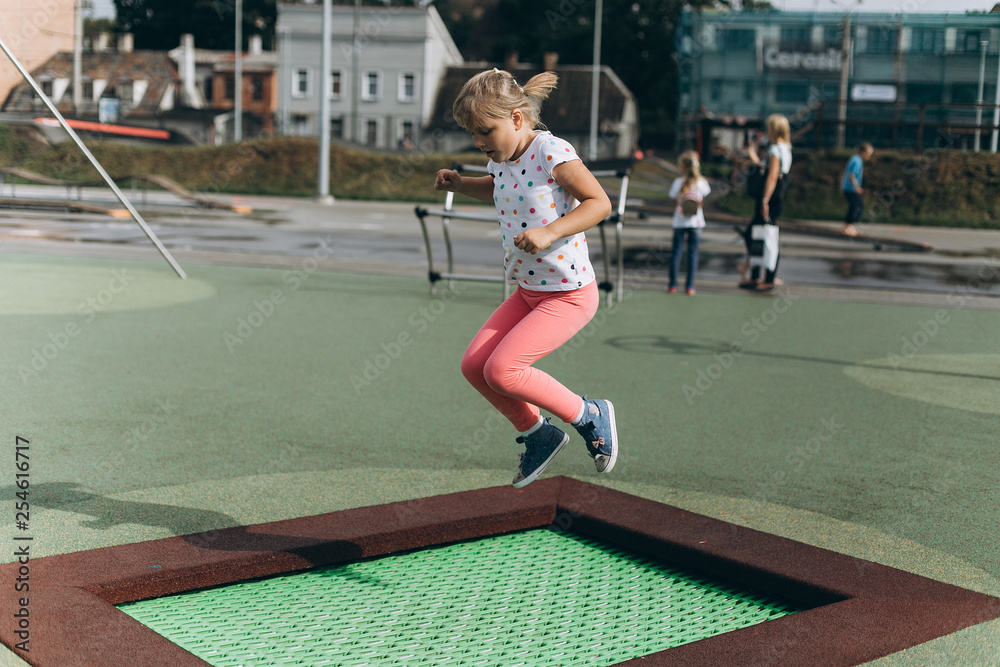 Cheerful adorable girl jumping outdoors in kindergarten.Happiness, sport, leisure, childhood, healthy concept