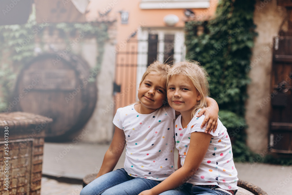 Cheerful happy girl travel together, hugging, holding hands and laughing outdoors in old town. Childhood, tourism, positive concept Cheerful happy girl travel together, hugging, holding hands and laughing outdoors in old town. Childhood, tourism, positive concept