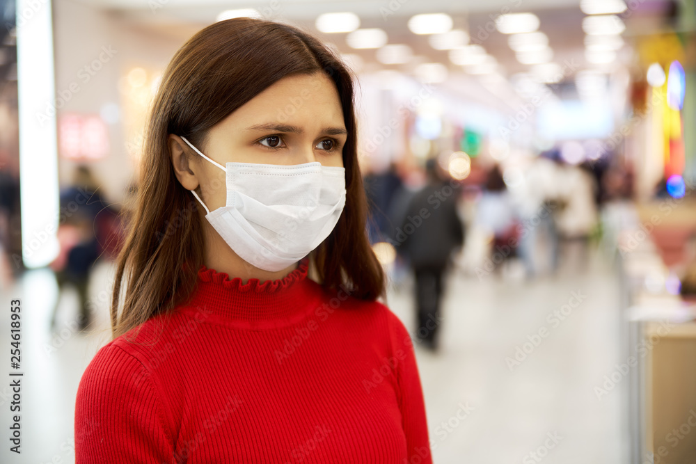 an alarmed young girl frowns and looks away. she is in the Mall and is afraid of infection. the concept of individual means of protection against biological contamination an alarmed young girl frowns and looks away. she is in the Mall and is afraid of infection. the concept of individual means of protection against biological contamination