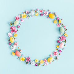 Easter eggs, colorful flowers on pastel blue background. Spring, easter concept. Flat lay, top view, copy space, square