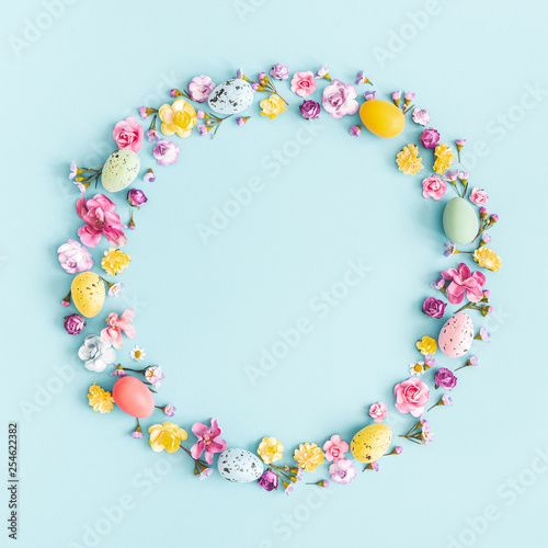 Easter eggs, colorful flowers on pastel blue background. Spring, easter concept. Flat lay, top view, copy space, square