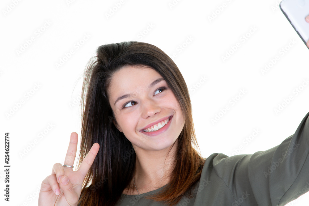 young smiling woman taking a selfie with smartphone making peace sign young smiling woman taking a selfie with smartphone making peace sign
