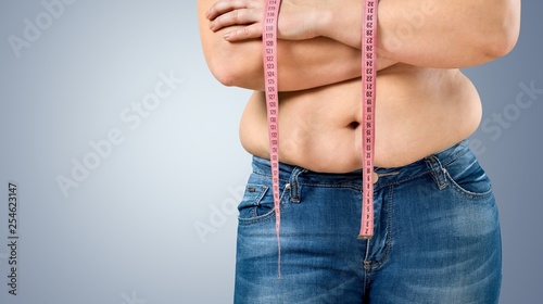 Overweight, fat woman measuring her stomach on background photo