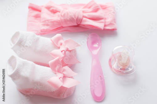 Baby girl care accessories and clothing on light background, top view