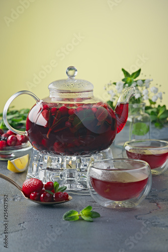 Berry tea in a glass teapot on a stone table