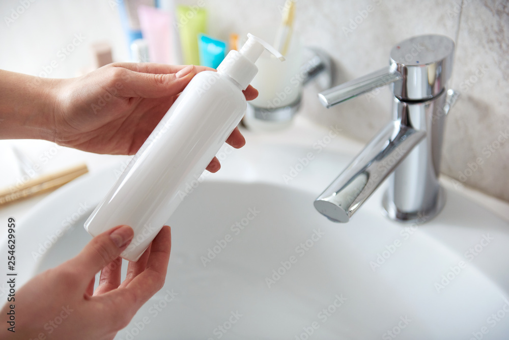 Young lady holding body lotion bottle in hand Young lady holding body lotion bottle in hand